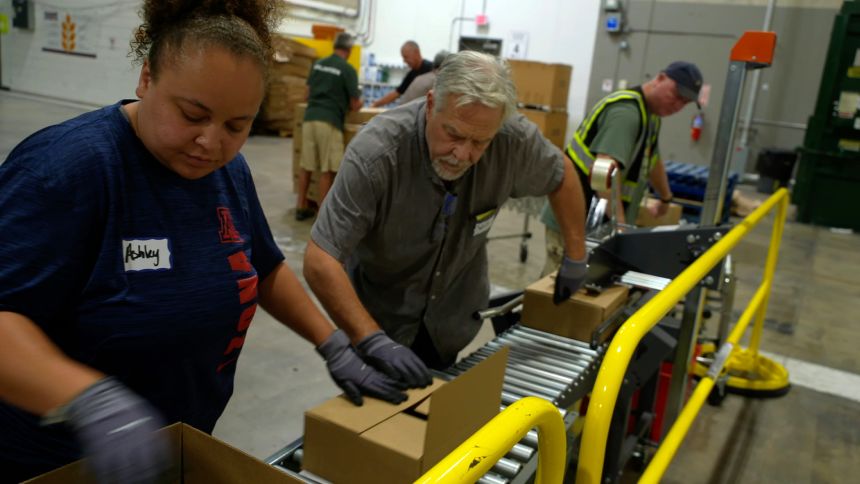 Volunteers work the supply line packing boxes of food at the Community Food Bank of Southern Arizona.
