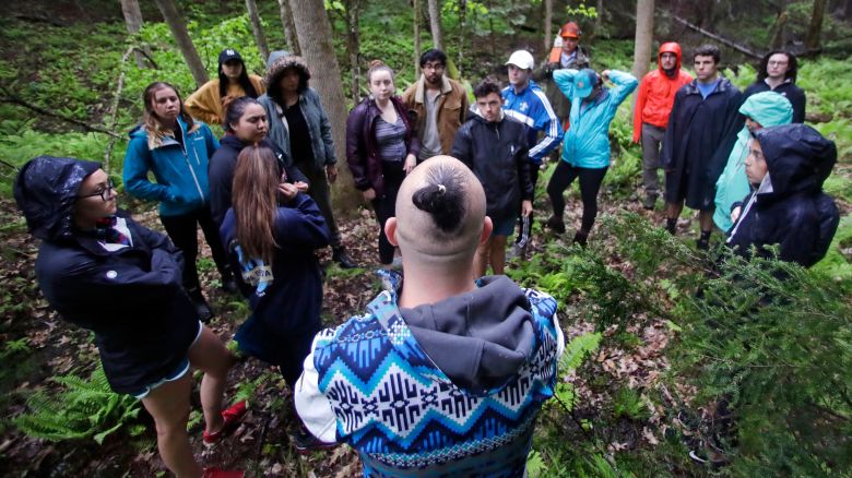 Native American basket maker Geo Neptune, of the Passamaquoddy tribe in Indian Township, Maine, center, talks with students before selecting a tree to cut during an outdoor class at Dartmouth College in May 22, 2018.