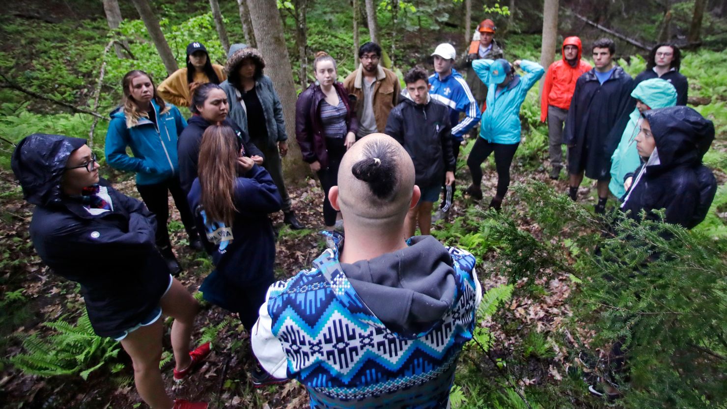 Native American basket maker Geo Neptune, of the Passamaquoddy tribe in Indian Township, Maine, center, talks with students before selecting a tree to cut during an outdoor class at Dartmouth College in May 22, 2018.