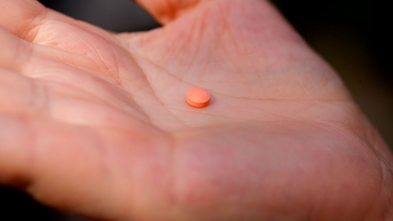 In this October 2021 photo, a woman holds an aspirin pill in New York.