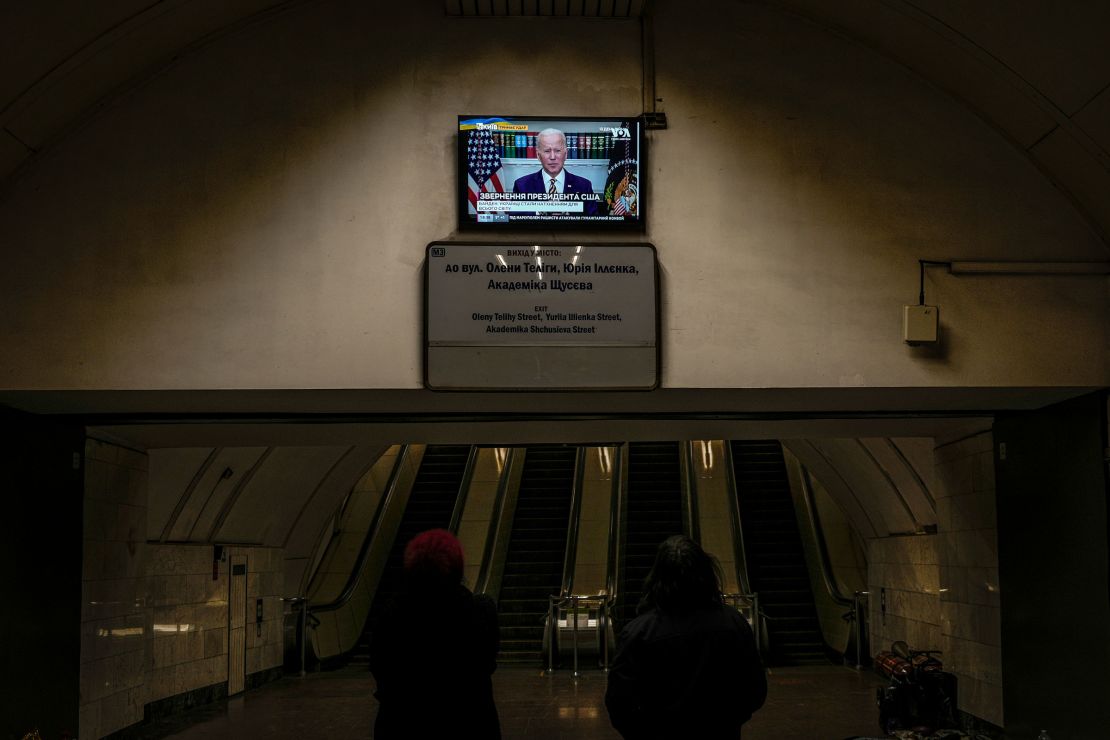 Two women watch US President Joe Biden making statements on a news channel in a subway station turned into a shelter in Kyiv, Ukraine, on March 8, 2022.