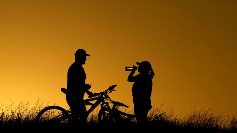 En esta foto de junio de 2023, ciclistas toman un descanso para beber agua durante un paseo nocturno en San Antonio.