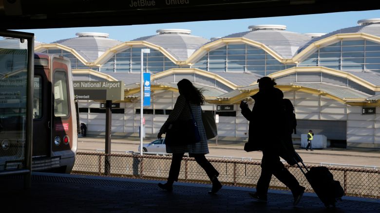 Travelers run to a waiting Metro train across from a terminal at Ronald Reagan Washington National Airport in Arlington, Virginia, in November 2022.