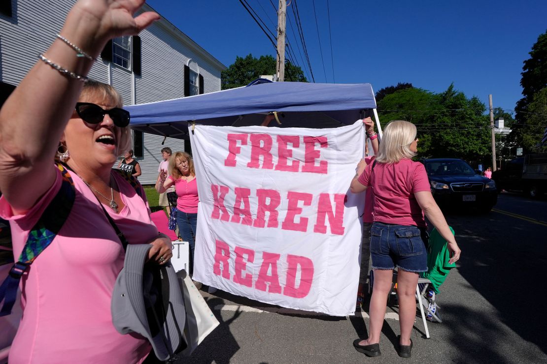 Eva Jenkins, of Bourne, Massachusetts, waves to passing cars as other supporters place a banner a block away from Norfolk Superior Court on Tuesday in Dedham, Massachusetts.