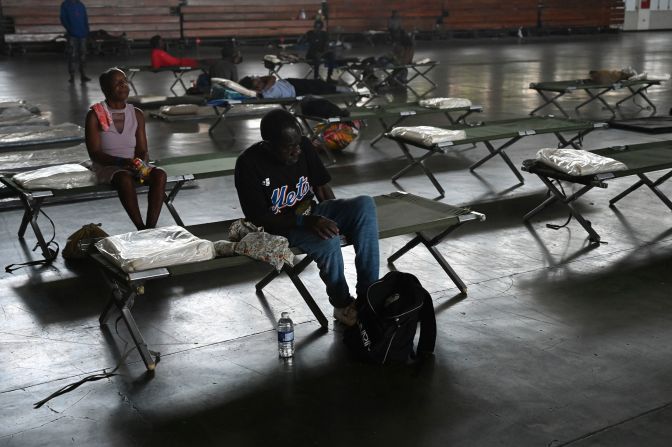 People sit on cots Thursday at the National Arena in Kingston, Jamaica. The arena was serving as a shelter in the aftermath of Beryl.