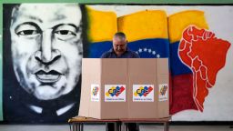 A voter chooses his candidate in front of a mural of late Venezuelan President Hugo Chavez during the presidential election in Caracas, Venezuela, Sunday, July 28.