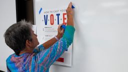 A poll worker hangs up signs at an early in-person voting site at Asheville-Buncombe Technical Community College on October 16 in Marshall, North Carolina.