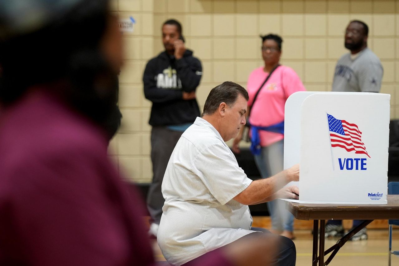 A voter casts his ballot while others wait in line for their opportunity to vote on Tuesday, November 5, in Jackson, Mississippi. 