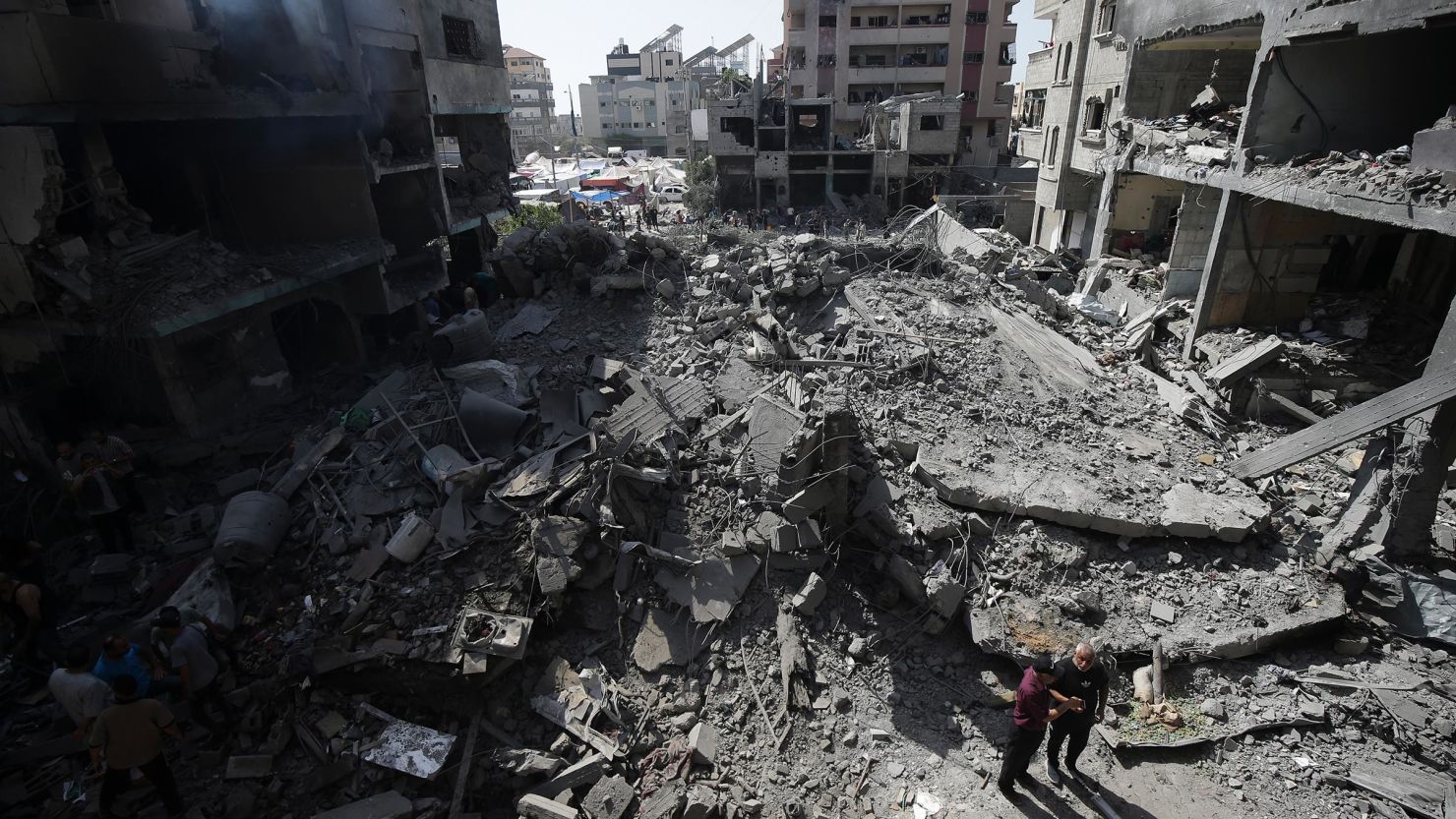 Des Palestiniens observent les conséquences d'un bombardement israélien dans le camp de réfugiés de Nuseirat, dans la bande de Gaza, en juin.