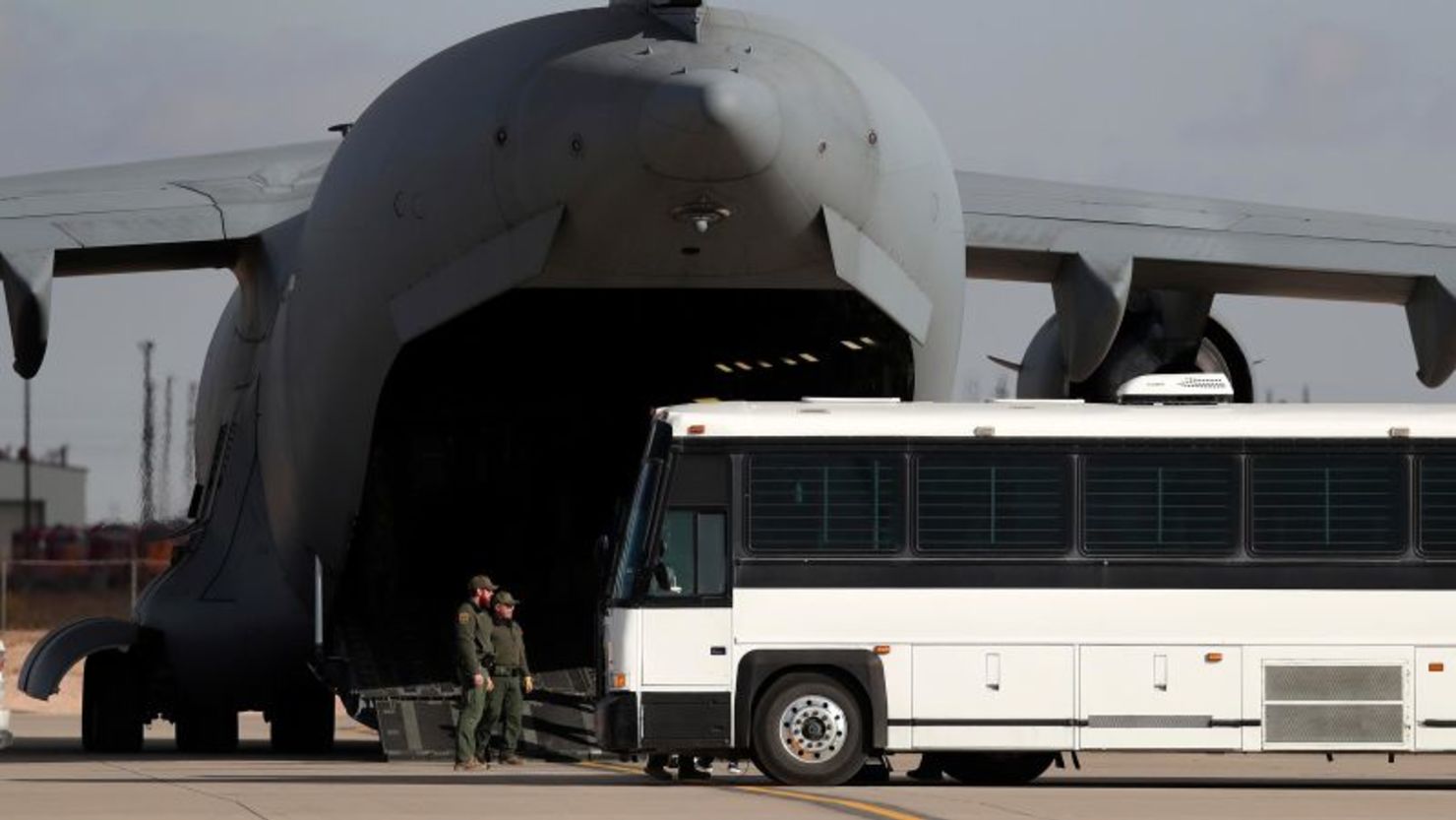 Una aeronave militar espera a inmigrantes que abordan un autobús en Fort Bliss, El Paso, Texas, el 30 de enero.