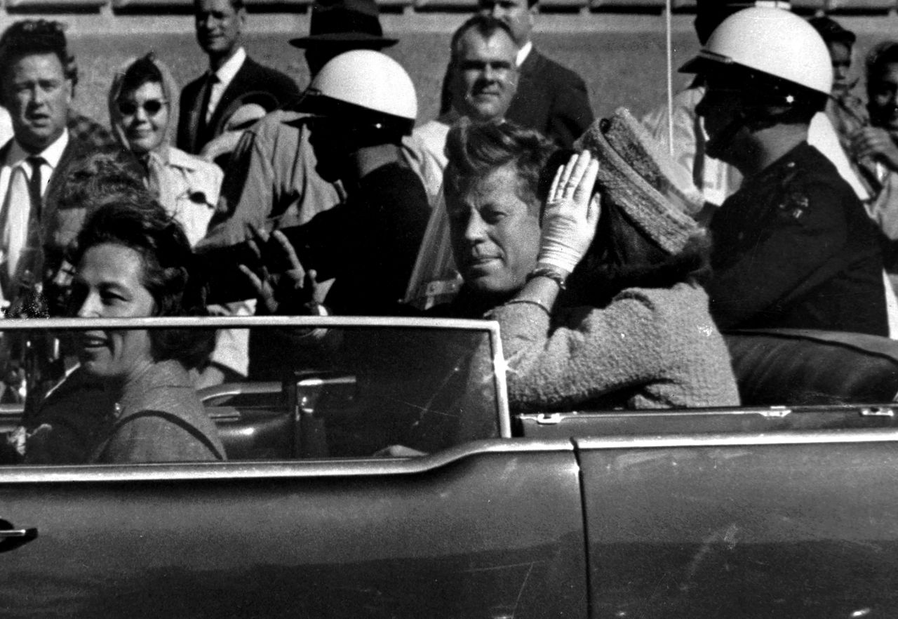 President John F. Kennedy waves from his car in a motorcade approximately one minute before he was shot on November 22, 1963, in Dallas. 