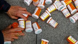 In this 2019 photo, a protester gathers containers that look like OxyContin bottles at an anti-opioid demonstration in front of the US Department of Health and Human Services headquarters in Washington, DC.