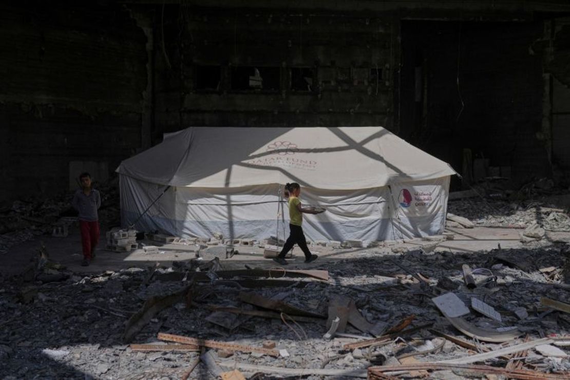 Una niña lleva una bandeja de comida junto a una tienda de campaña que alberga a palestinos desplazados dentro del destruido Centro Cultural Rashad Al-Shawa en la ciudad de Gaza, el 21 de abril.