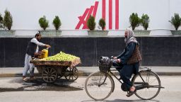 A cyclist passes in front of the former US embassy while a vendor waits for customers, in Kabul, Afghanistan, on June 5. 