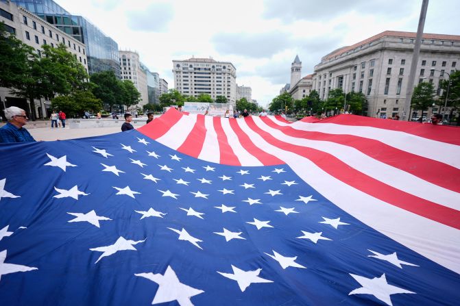 People hold a large American flag at Freedom Plaza before the parade on Saturday.