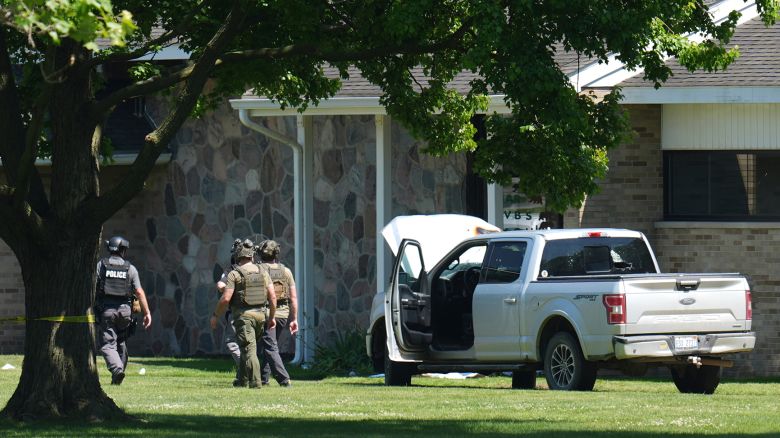 Police walk by an idle vehicle near CrossPointe Community Church in Wayne, Michigan, on June 23.