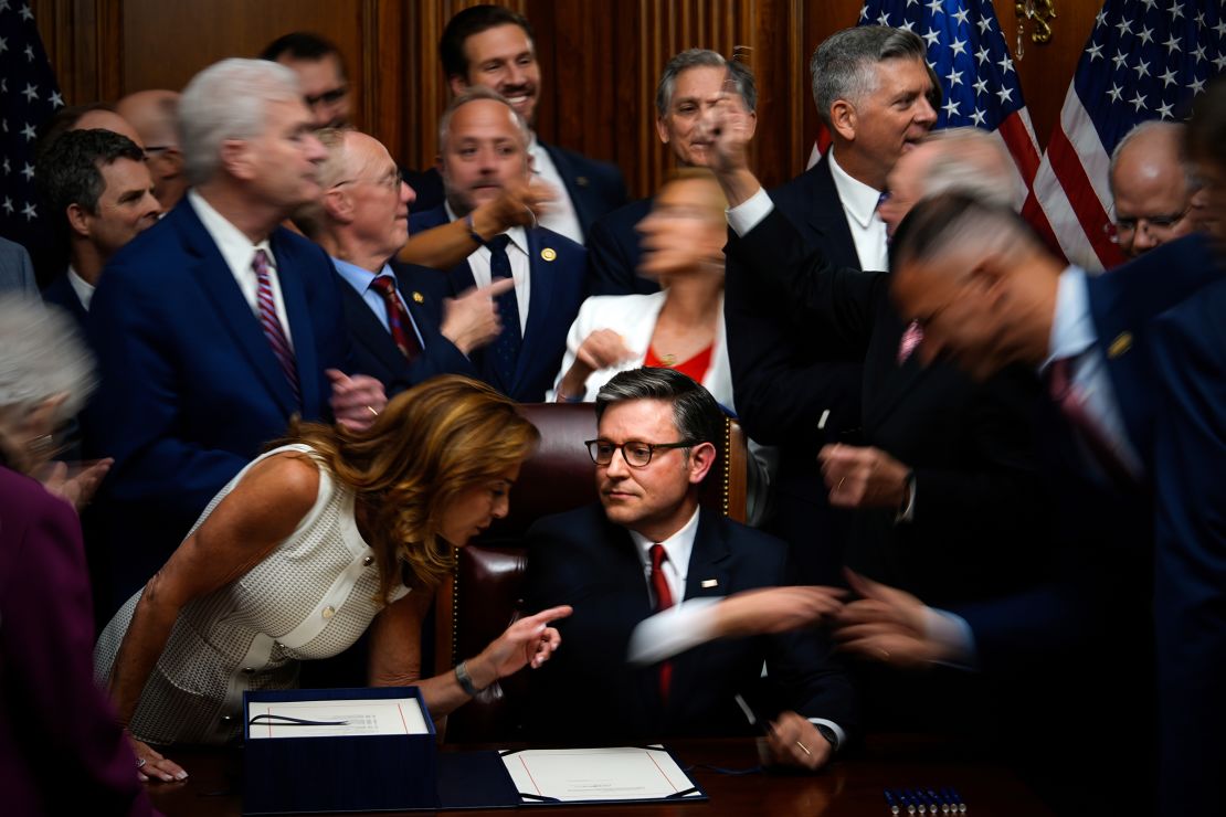 Republican members of Congress reach to shake hands with House Speaker Mike Johnson after Johnson signed President Donald Trump's agenda bill.
