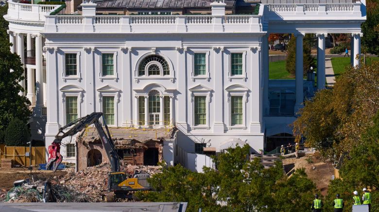 Construction workers, bottom right, atop the U.S. Treasury, watch as work continues on a largely demolished part of the East Wing of the White House, Thursday, Oct. 23, 2025, in Washington, before construction of a new ballroom.