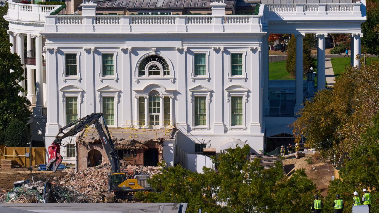 Construction workers, bottom right, atop the U.S. Treasury, watch as work continues on a largely demolished part of the East Wing of the White House, Thursday, Oct. 23, 2025, in Washington, before construction of a new ballroom.