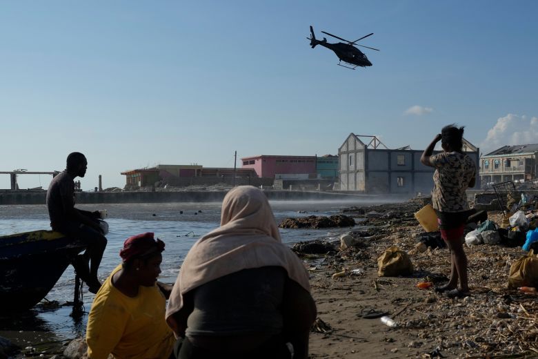 Residents watch a helicopter depart after dropping off medical supplies in Black River, Jamaica, on Thursday.