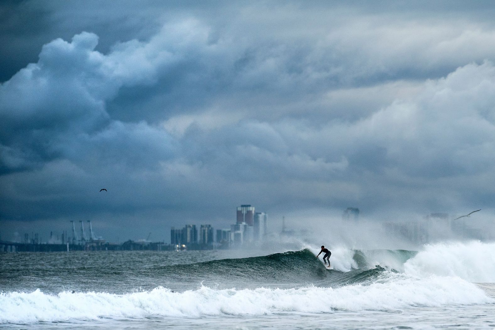 A surfer rides a wave as clouds gather above the Bolsa Chica State Beach in Orange County, California, on Saturday, November 15.