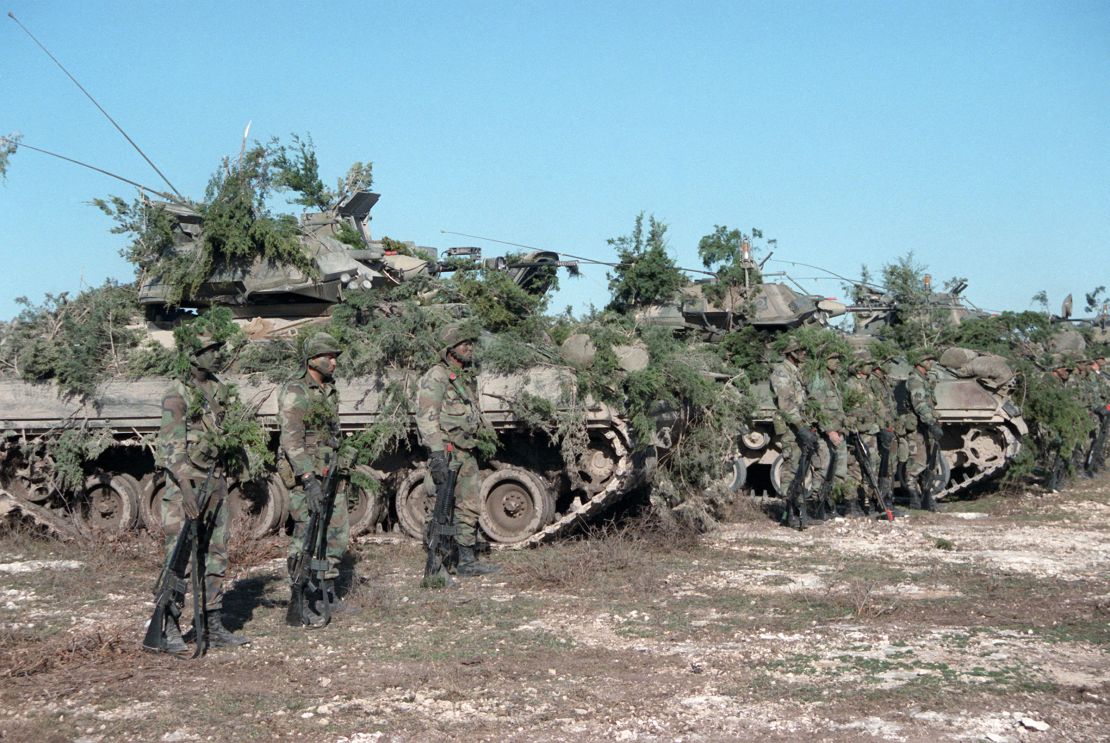 Soldiers stand beside their camouflaged M2 Bradley infantry fighting vehicles at the Shell Point training area in Fort Hood, Texas, in 1986.