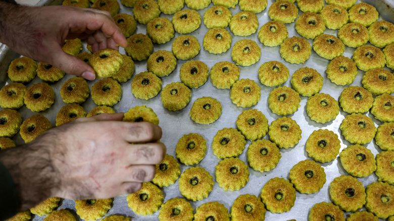 A Palestinian baker lays out fresh ma'amoul, traditional pastries filled with dates or nuts, on a tray on the eve of Eid al-Fitr in Jerusalem on April 20, 2023.