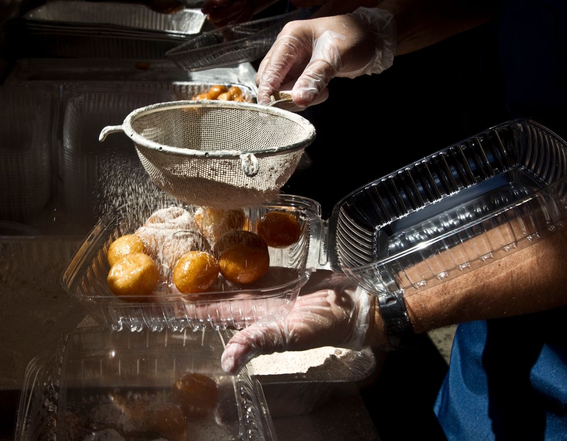 Powdered sugar is sifted on honey puffs to make l'geimats.