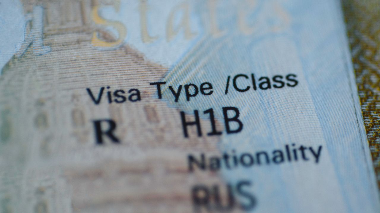 Fragment of H1B visa (for specialty workers) stamp in passport, blurred april calendar on background. H1B visa program deadline concept. Close up view.