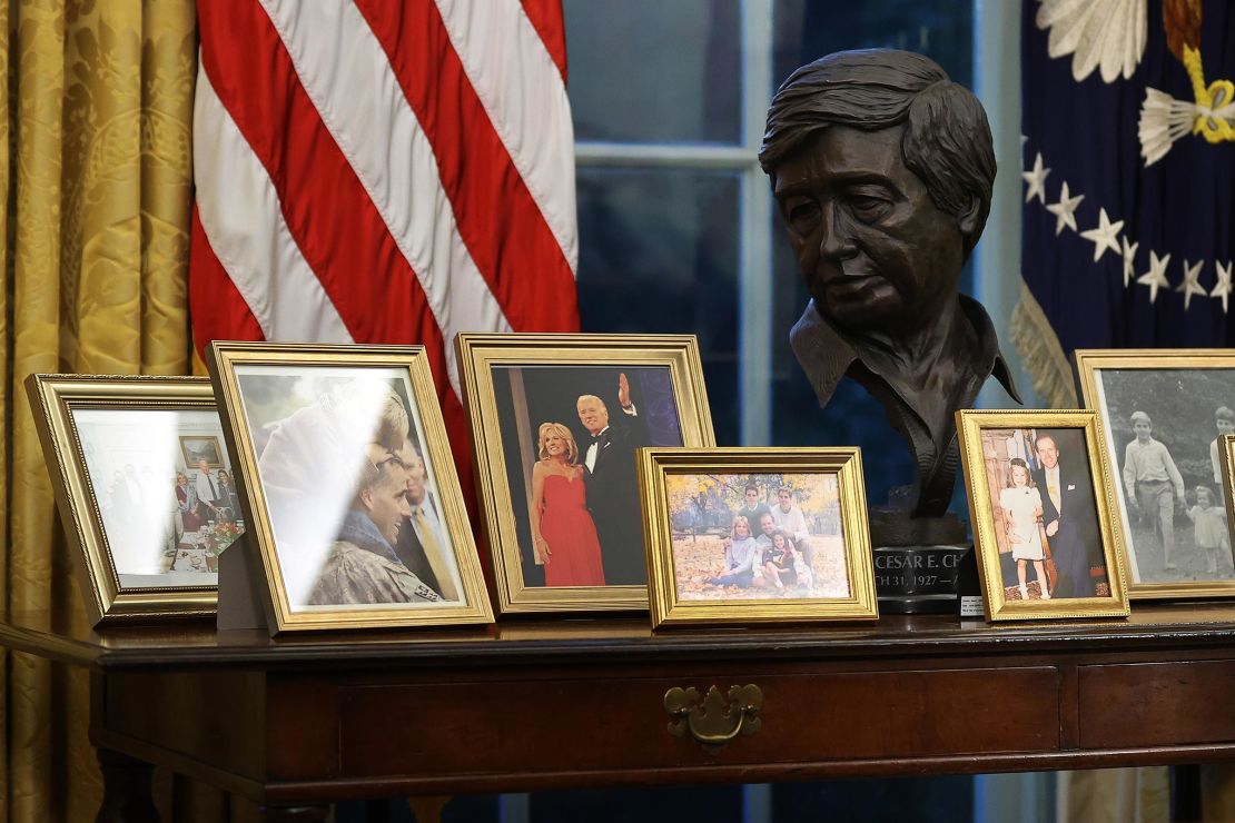 A sculpted bust of Cesar Chavez is seen with a collection of framed photos on a table as US President Joe Biden prepares to sign a series of executive orders at the Resolute Desk in the Oval Office just hours after his inauguration on January 20, 2021 in Washington, DC. 