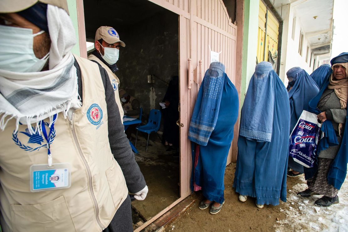 Women in burqas line-up as the UN World Food Program (WFP) distributes a critical monthly food ration, with food largely supplied by the US Agency for International Development, to 400 families south of Kabul in Pul-e Alam, Afghanistan, on January 17, 2022. 