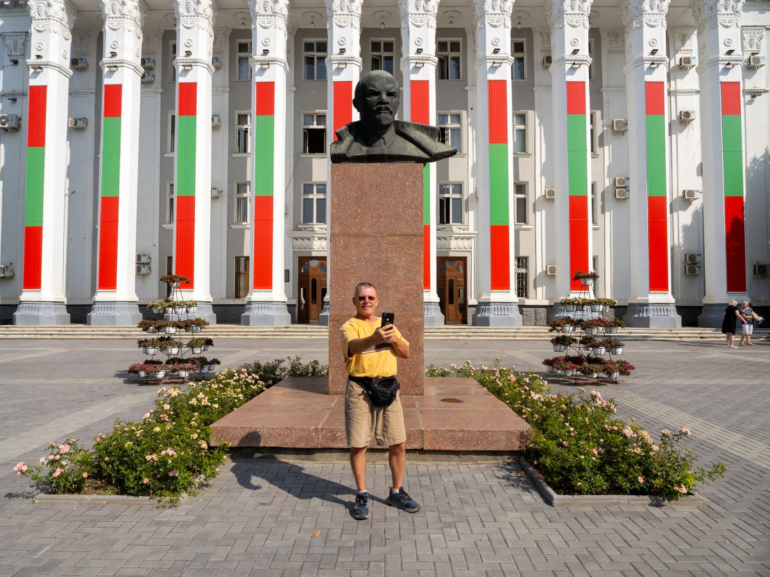 A visitor takes a selfie with a bust of Lenin in front of the parliament building in Tiraspol, Transnistria, in September 2023.