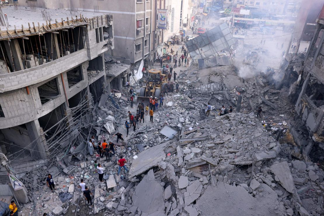 Palestinian civilians and rescuers help clear the rubble in the heavily bombarded city center of Khan Yunis in the southern Gaza Strip following overnight Israeli shelling, on October 10, 2023. 