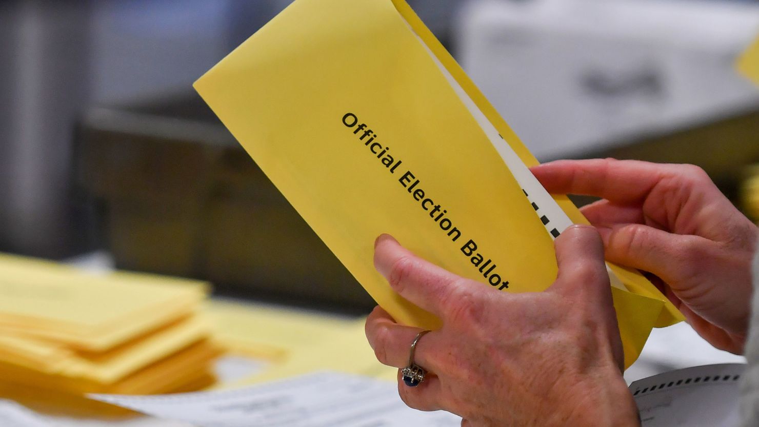 In this November 2023 photo, a woman takes a mail-in ballot from an envelope at a polling station in Pennsylvania. 