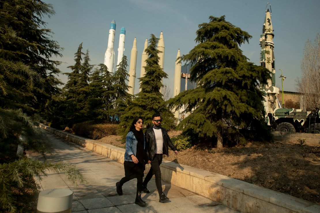 An Iranian couple walking in a park, with exhibited Iranian missiles in the background on January 20, 2024 in Tehran, Iran.