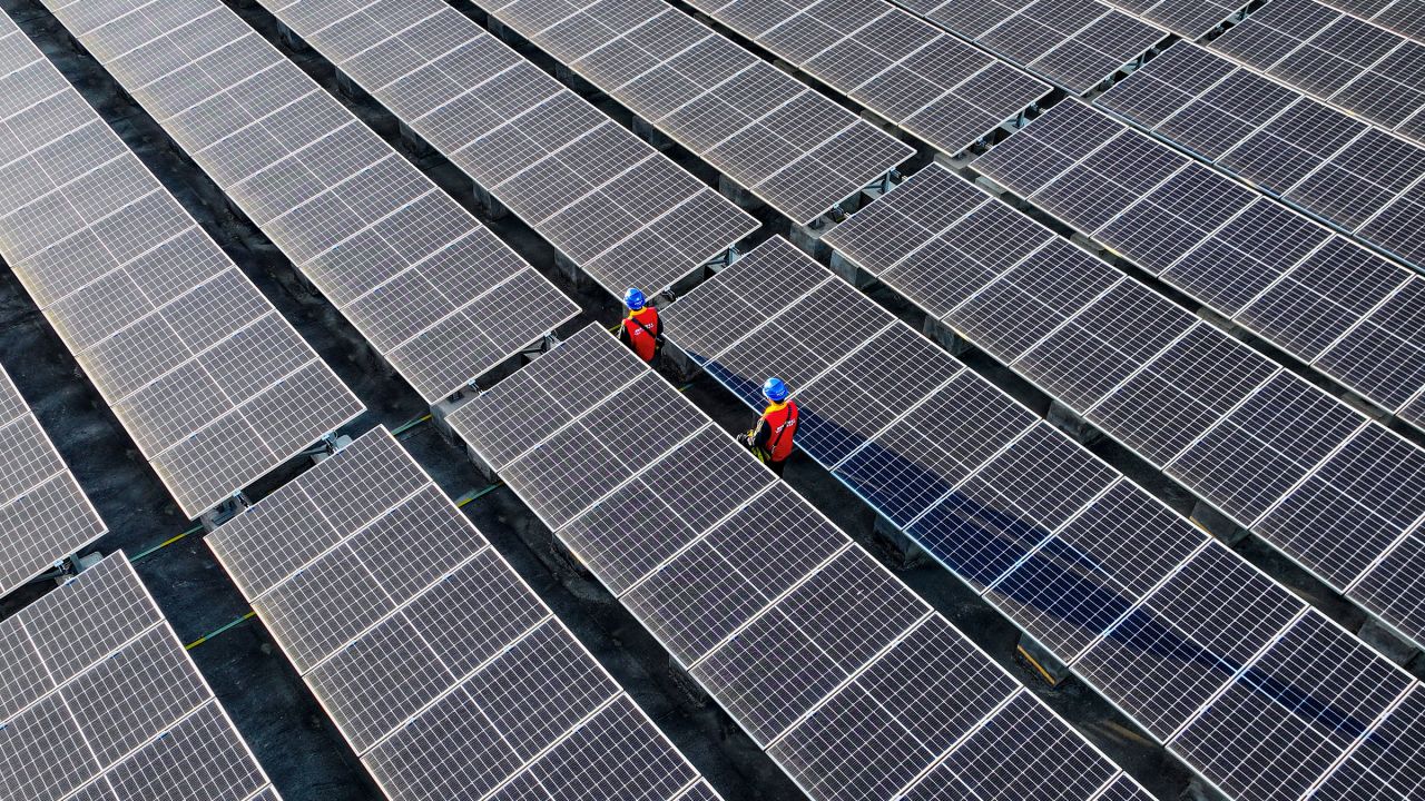 Workers inspect solar panels at a rooftop of a power plant in Fuzhou, in southern China's Fujian province in February. 