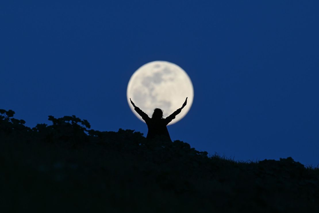 A full Moon named the ''Snow Moon'' rises over San Francisco Bay at the Seal Point Park as a woman stands in San Mateo, California, on February 23, 2024. 