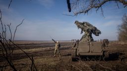 A member of Ukraine's 72nd Brigade Anti-air unit points to the direction of a Russian Zala reconnaissance drone sighted overhead as they prepare to fire a Strela-10 anti-air missile system on February 23 near Marinka, Ukraine. 