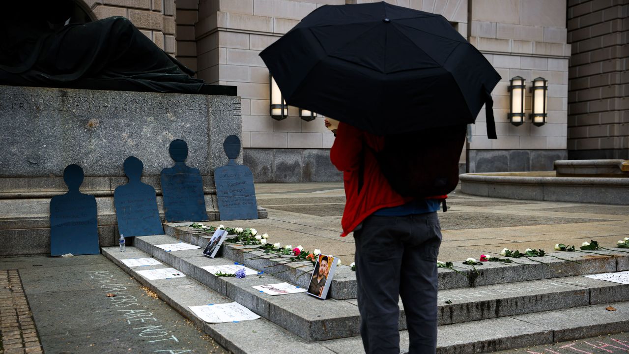 A person looks at flowers and signs on the ground in front of the US Agency for International Development building at a vigil for aid workers killed in the Gaza war on April 11, 2024 in Washington, DC.