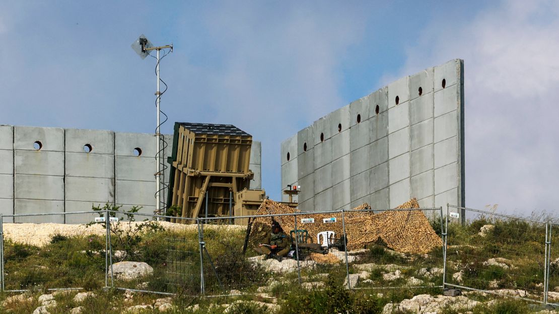 An Israeli soldier takes up a position in front of a battery of an Iron Dome air defense system near Jerusalem on April 15, 2024.