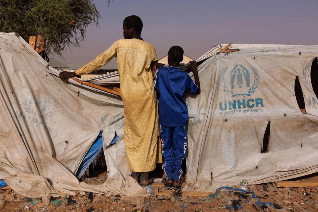 Two boys peer over a UNHCR aid tent as newly arrived refugees from Darfur in Sudan, gather at a relocation camp near the border on April 19 in Adre, Chad. 