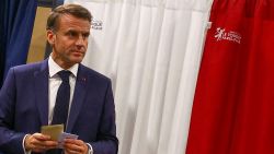 France's President Emmanuel Macron exits a polling booth, adorned with curtains displaying the colors of the flag of France, before casting his ballot for the European Parliament election at a polling station in Le Touquet, northern France on June 9, 2024.