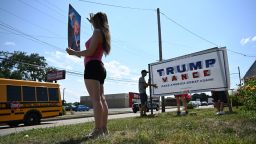 Julianna Grooms holds a photo of former President Donald Trump as neighbors help she and her mother secure a Trump yard sign that they used tape to add the name of Trump's running mate J.D. Vance outside their home on July 16, 2024, in Bethel Park, Pennsylvania.