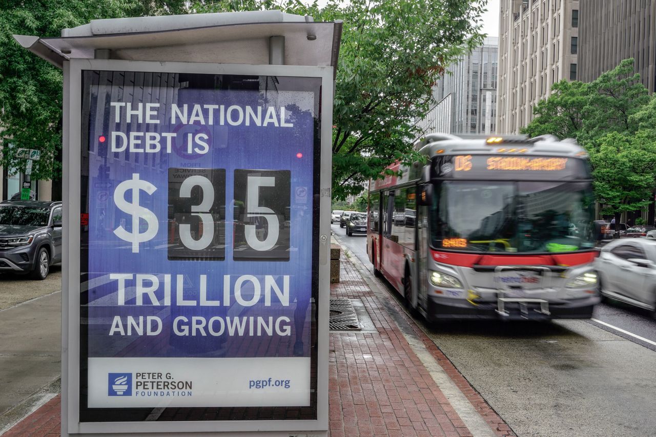 A Metrobus approaches a bus shelter at 18th and K St's NW where a poster and electronic billboard displays the current US national debt on August 8 in Washington, DC. 