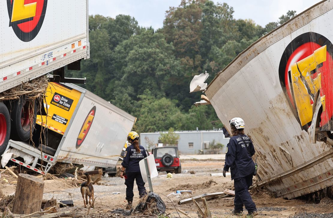 Members of the FEMA Urban Search and Rescue Task Force search a flood damaged area with a search canine in the aftermath of Hurricane Helene along the Swannanoa River on October 4 in Asheville, North Carolina. 