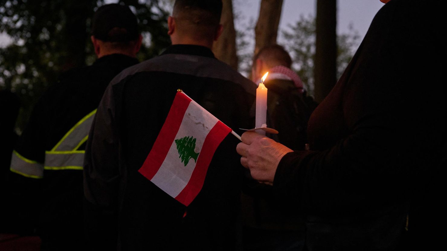 A person holds a small flag of Lebanon during a candlelight vigil in Dearborn, Michigan. 