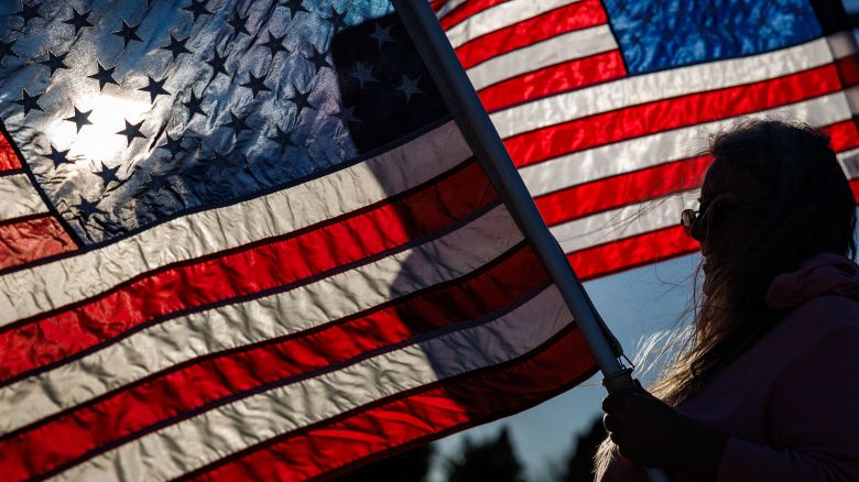 People wave American flags during rush hour in Easton, Pennsylvania on November 1, 2024.