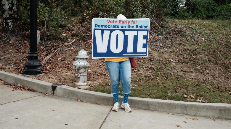 A supporter of the Democratic Party holds placards calling for voting in support of Democrats in Clarkston, Georgia, on November 4, 2024.