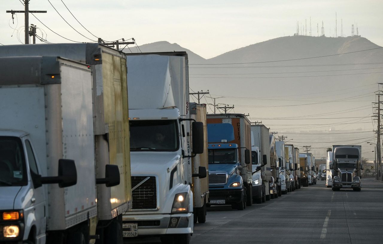 Trucks wait on a queue to cross to the US next to the border wall at the Otay commercial crossing port in Tijuana, Baja California state, Mexico on November 26, 2024. President-elect Trump said Monday he would impose a 25 percent tariff on all imports from Mexico and Canada as one of his first actions upon becoming US president in January. 