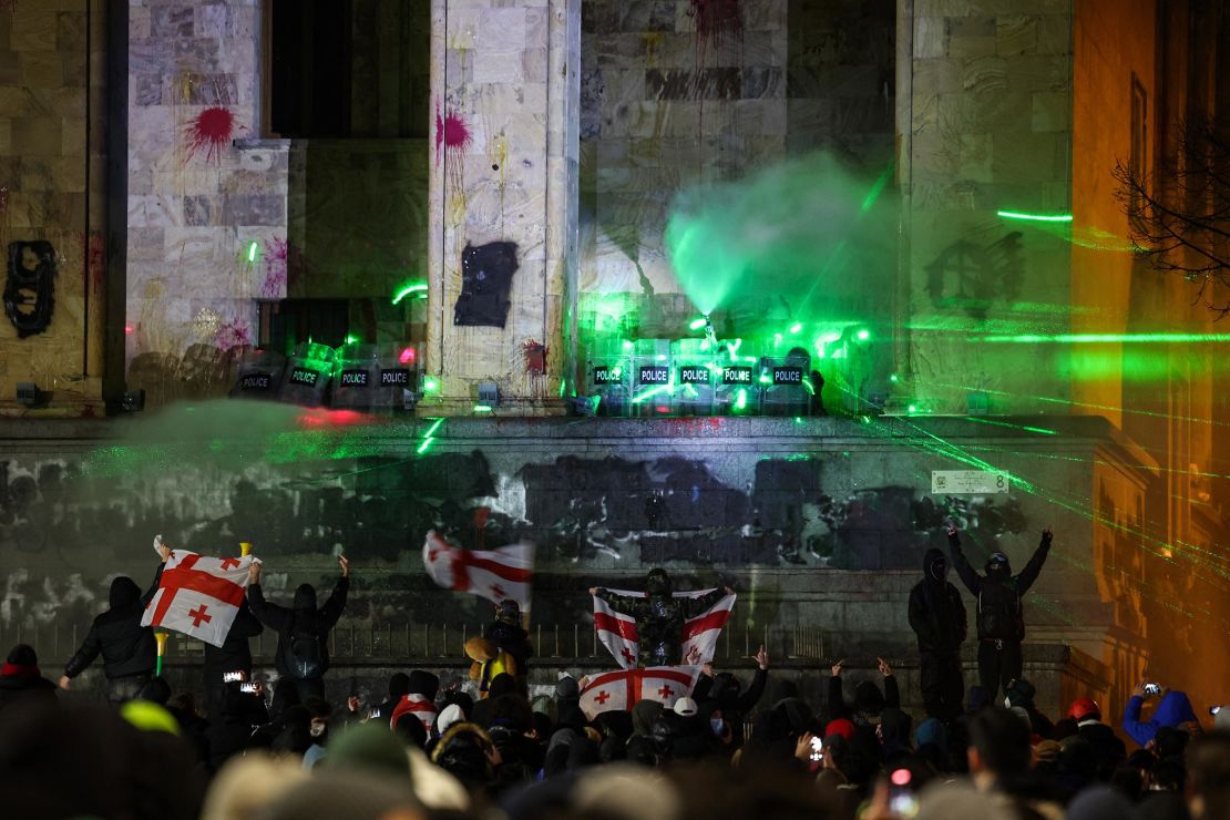 Police forces secure the parliament building as anti-government protesters rally outside it during a sixth consecutive day of mass demonstrations against the government's postponement of European Union accession talks until 2028, in central Tbilisi on December 3.